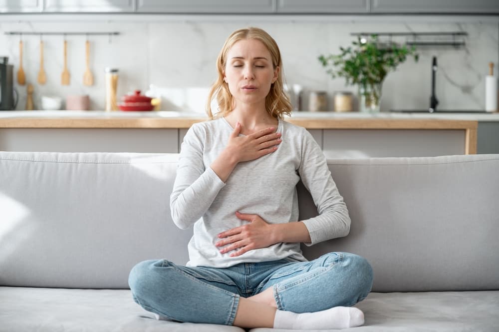 woman-sitting-on-couch-doing-breathing-exercises