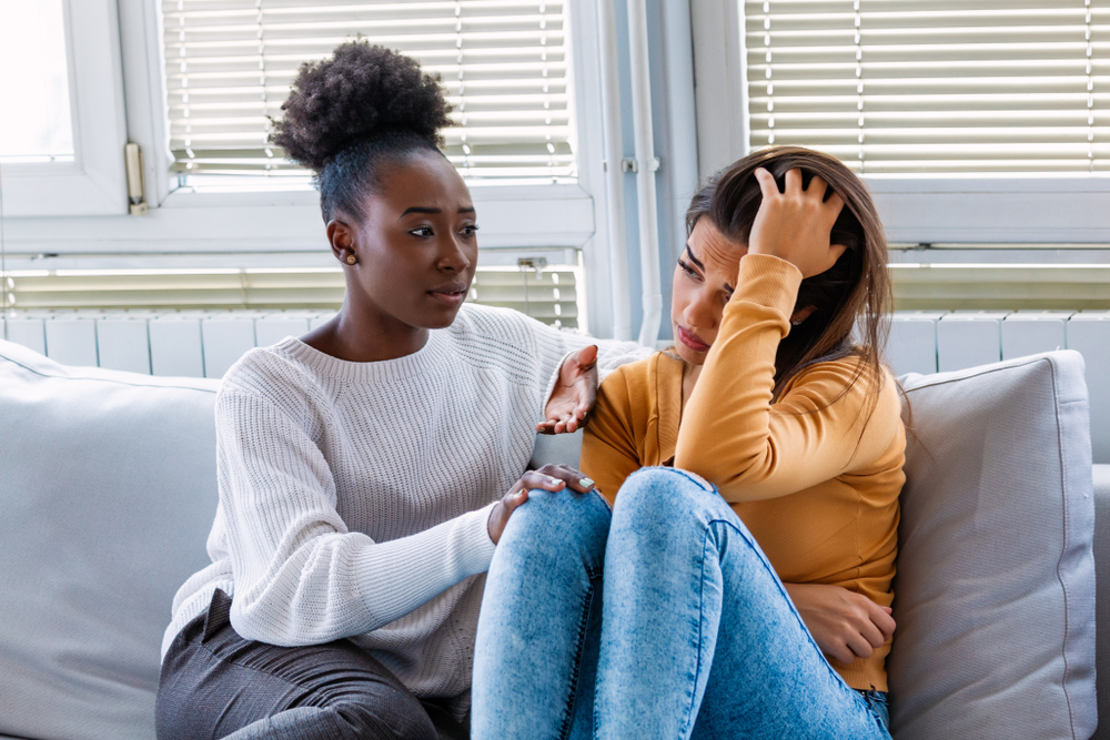 woman listening to her worried friend on a couch